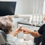 gray-haired-lady-holding-dental-implant-model