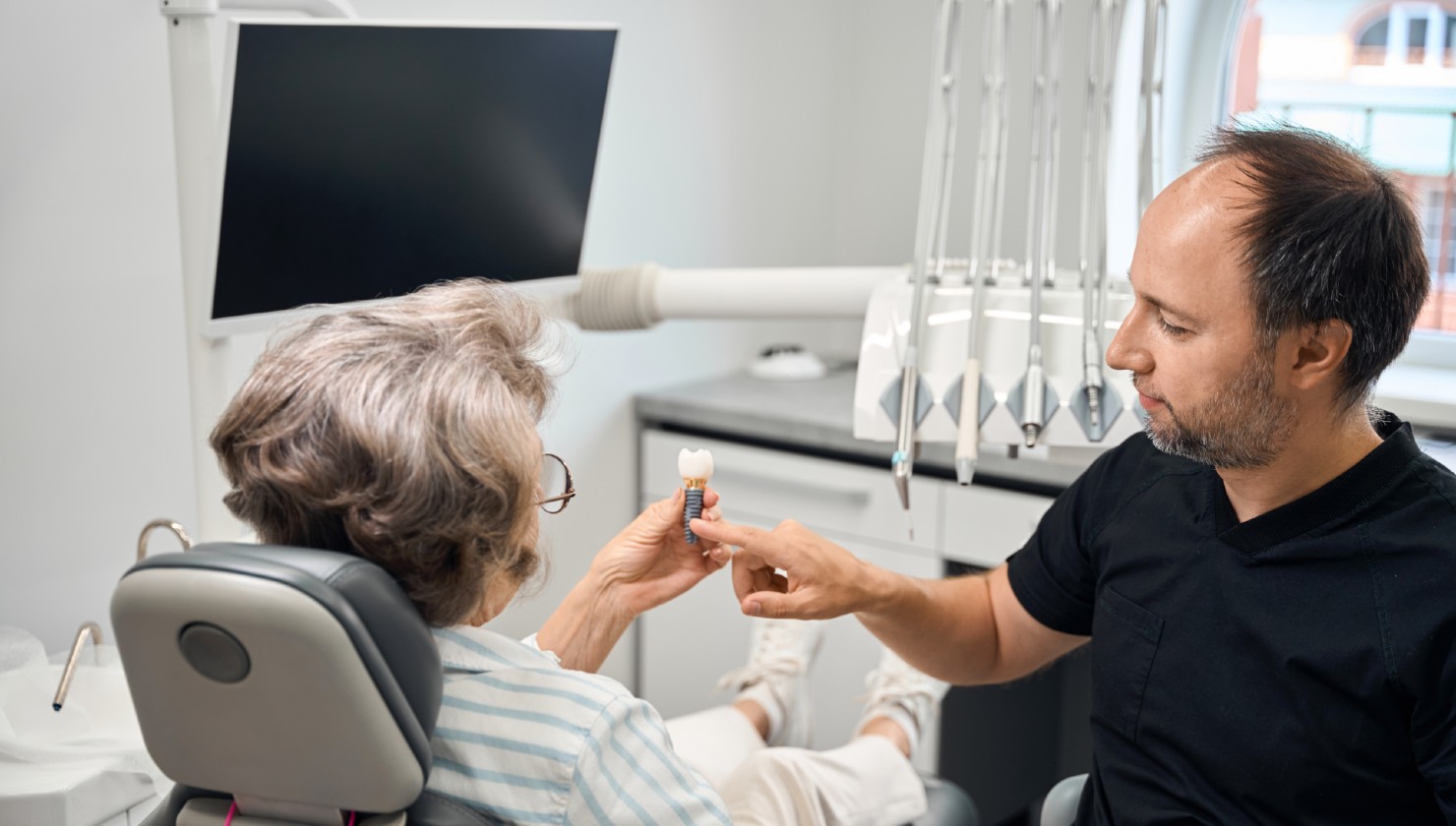 gray-haired-lady-holding-dental-implant-model